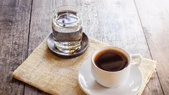 Why should a glass of water be served with a cup of coffee?